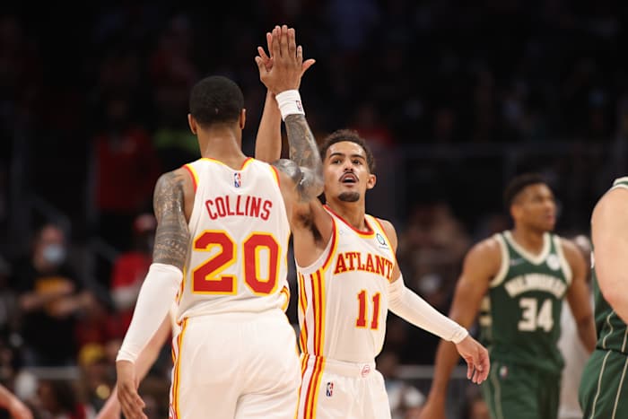 Trae Young and John Collins high-five each other.